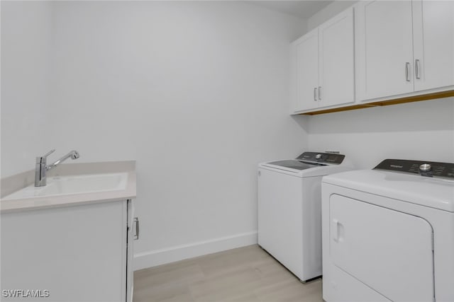 laundry area featuring cabinets, washer and clothes dryer, and sink