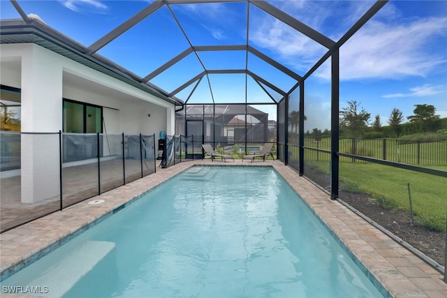 view of swimming pool featuring a yard, a patio, and glass enclosure