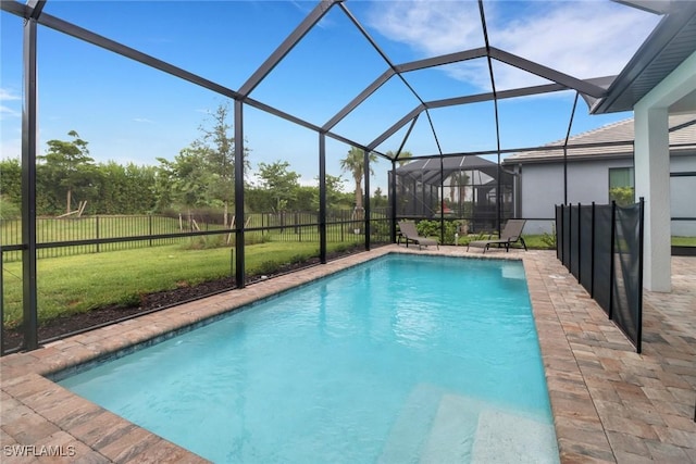 view of pool with a yard, glass enclosure, and a patio area