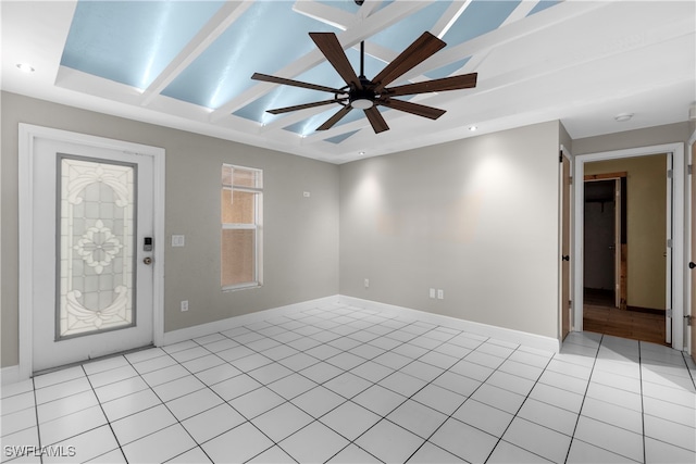 tiled spare room featuring ceiling fan and a raised ceiling