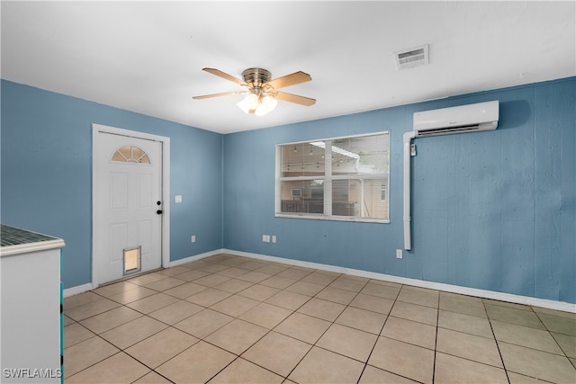 tiled spare room with ceiling fan and a wall mounted AC