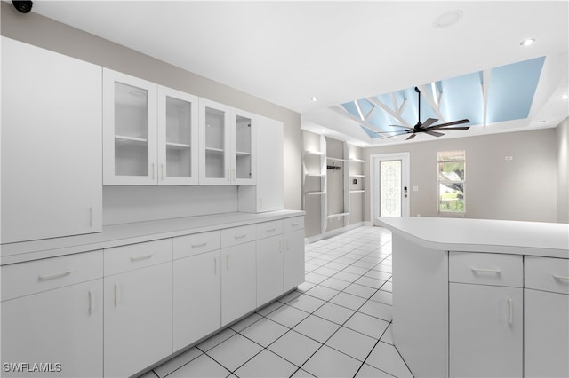 kitchen with ceiling fan, white cabinets, a raised ceiling, and light tile patterned floors