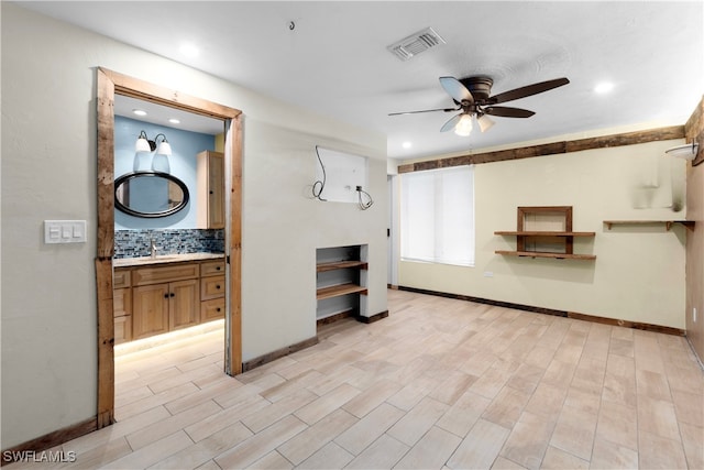 unfurnished living room with ceiling fan, sink, and light wood-type flooring