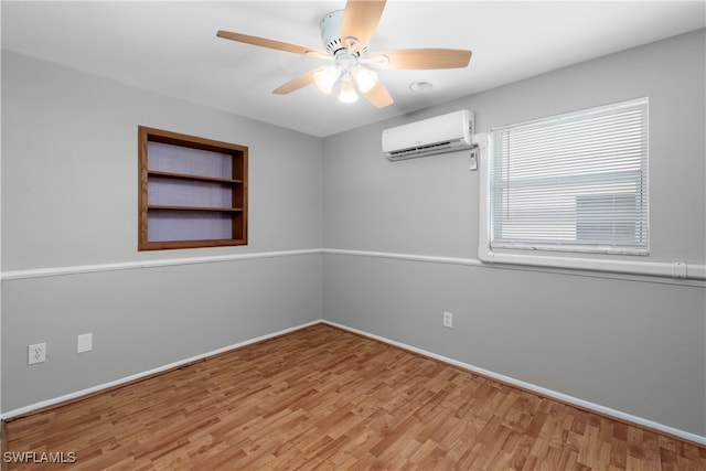 spare room with ceiling fan, light wood-type flooring, and a wall unit AC