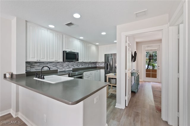 kitchen featuring appliances with stainless steel finishes, kitchen peninsula, sink, and white cabinets