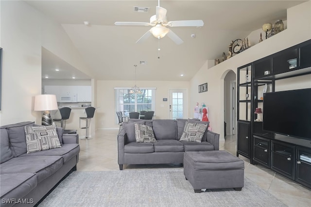 living room featuring high vaulted ceiling, light tile patterned floors, and ceiling fan with notable chandelier