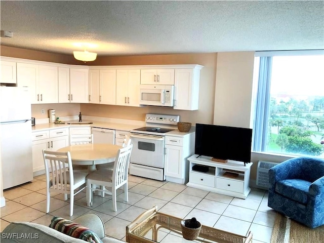 kitchen featuring white cabinets, a textured ceiling, white appliances, and a wealth of natural light