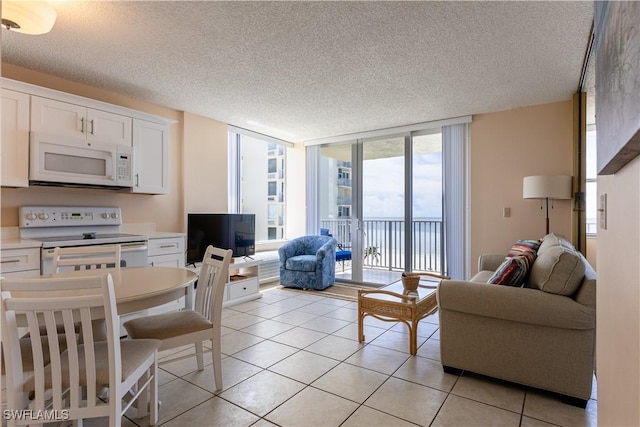 living room featuring a textured ceiling, floor to ceiling windows, and light tile patterned floors