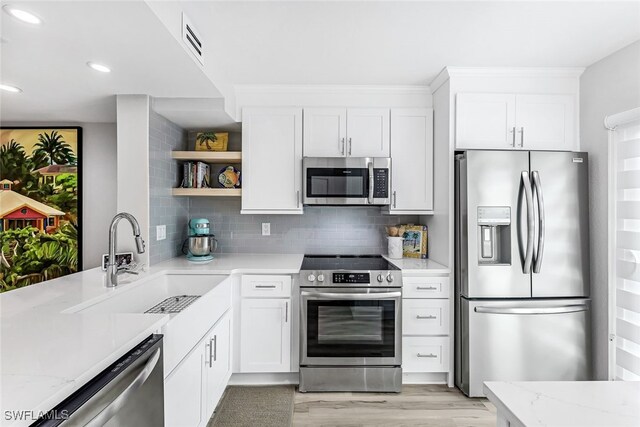 kitchen with decorative backsplash, light hardwood / wood-style flooring, appliances with stainless steel finishes, light stone countertops, and sink