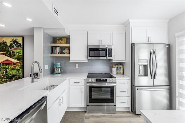 kitchen with white cabinets, appliances with stainless steel finishes, open shelves, and a sink