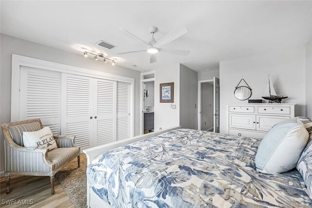 bedroom featuring ceiling fan, rail lighting, light wood-type flooring, and a closet