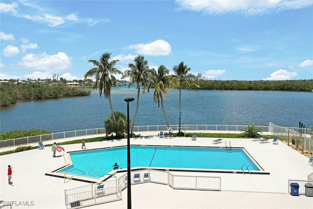 pool with a patio area, a water view, and fence