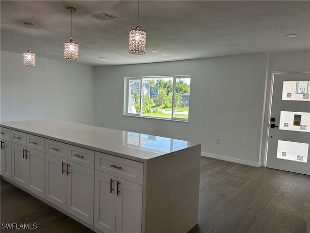 kitchen with white cabinetry, dark hardwood / wood-style floors, hanging light fixtures, and light stone counters