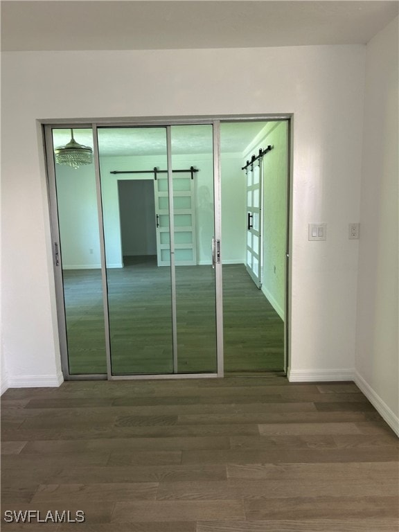 unfurnished bedroom with hardwood / wood-style floors, a barn door, and a closet