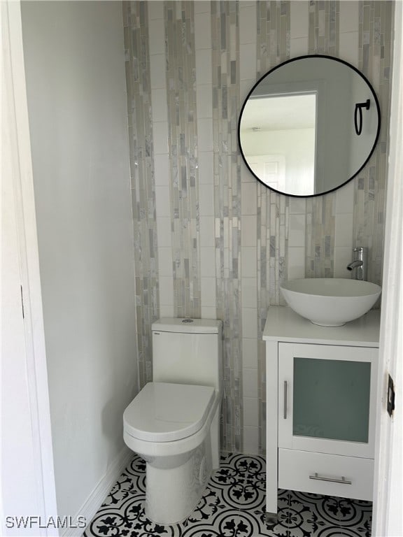 bathroom featuring tile patterned flooring, tile walls, toilet, and vanity