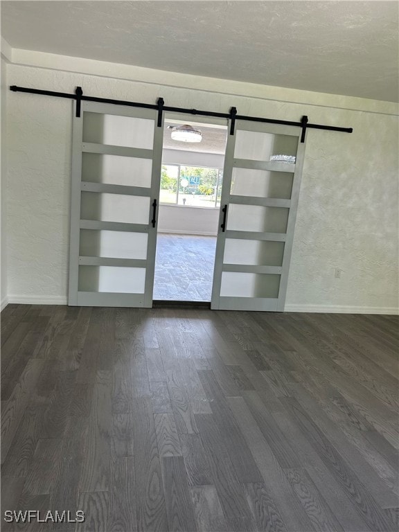 unfurnished room featuring built in shelves, wood-type flooring, and a barn door