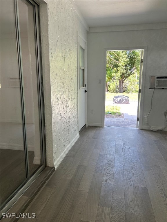 doorway to outside featuring a wall mounted AC and wood-type flooring