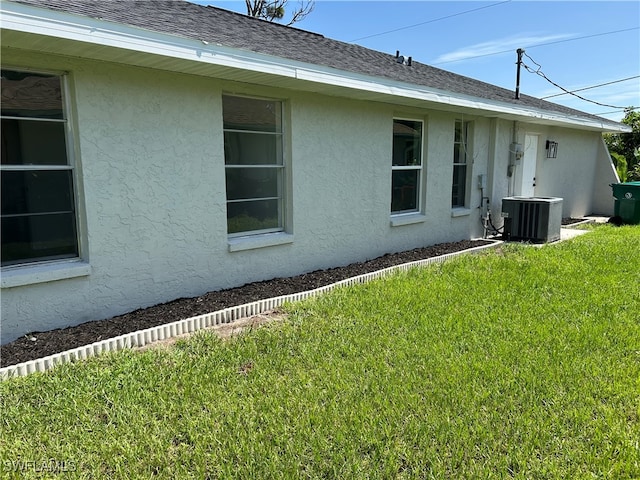 view of side of home featuring central air condition unit and a lawn