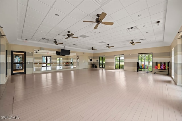 interior space with ceiling fan, a drop ceiling, light hardwood / wood-style flooring, and a tray ceiling