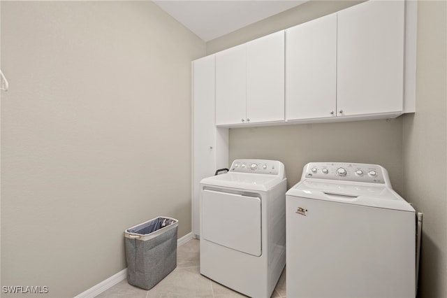 laundry area featuring light tile patterned floors, washing machine and clothes dryer, and cabinets