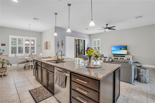 kitchen with stainless steel dishwasher, pendant lighting, light stone counters, light tile patterned floors, and sink