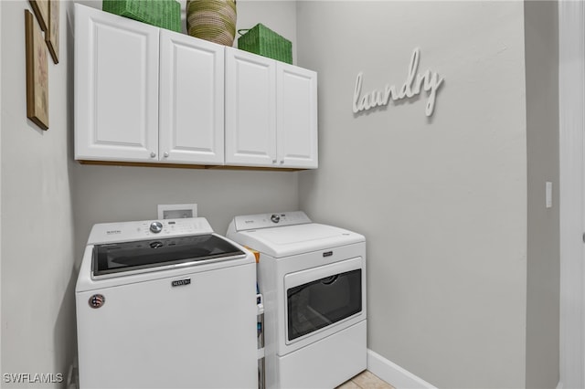 laundry room featuring separate washer and dryer, light tile patterned floors, and cabinets