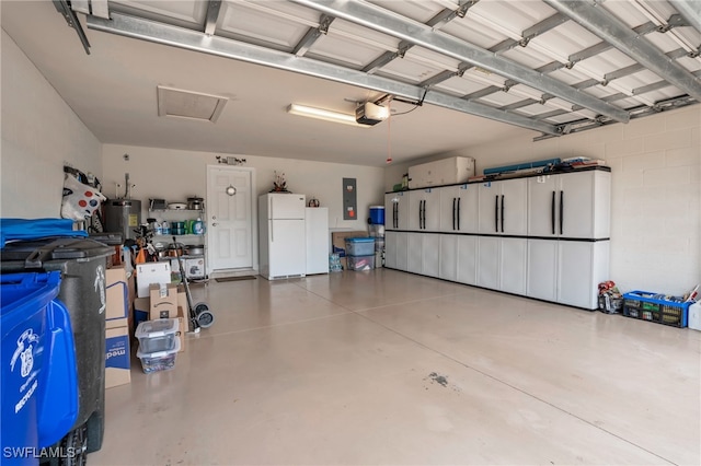 garage featuring electric water heater, a garage door opener, white refrigerator, and electric panel