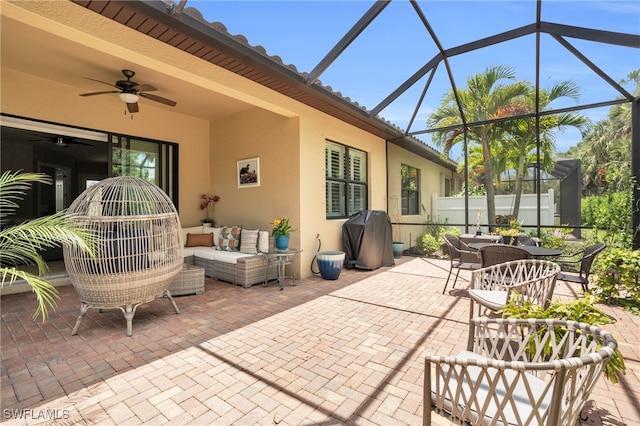 view of patio featuring ceiling fan, glass enclosure, outdoor lounge area, and area for grilling