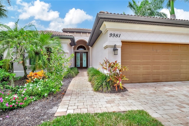 view of exterior entry with a garage and french doors