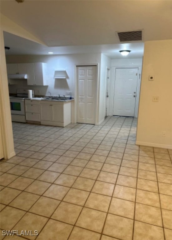 kitchen featuring light tile patterned floors, stove, and white cabinetry