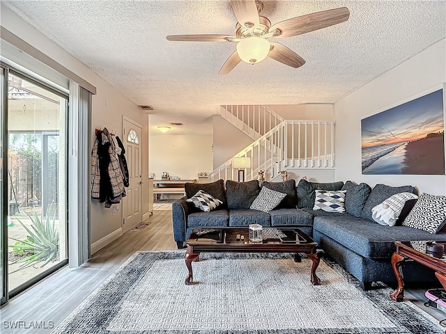 living room with light hardwood / wood-style floors, a textured ceiling, and ceiling fan