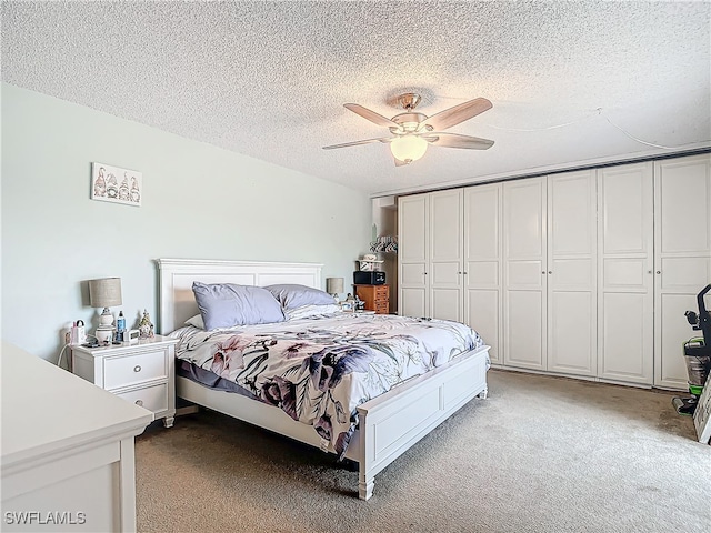 carpeted bedroom with ceiling fan, a textured ceiling, and a closet