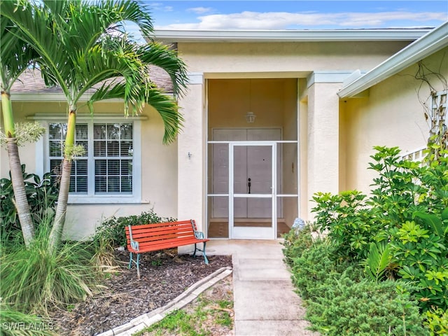 property entrance featuring stucco siding and a shingled roof