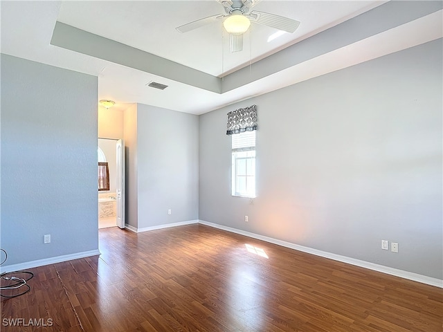 unfurnished room with a tray ceiling, ceiling fan, and dark hardwood / wood-style floors