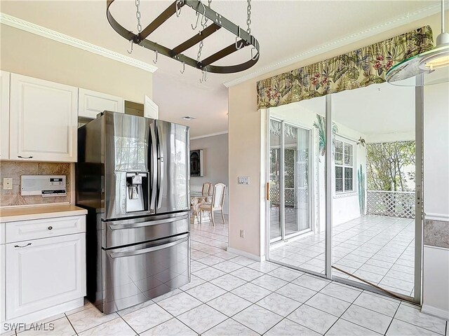 kitchen with white cabinets, backsplash, light tile patterned floors, stainless steel fridge with ice dispenser, and ornamental molding