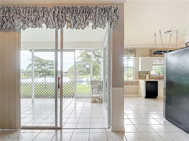 doorway featuring a water view, light tile patterned floors, sink, and ornamental molding