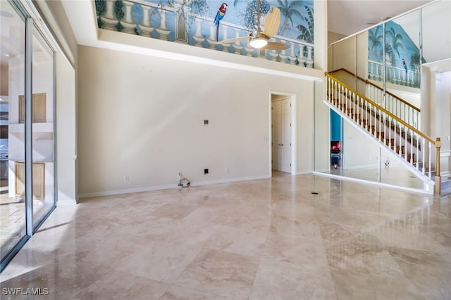 unfurnished living room featuring a towering ceiling, plenty of natural light, and ceiling fan