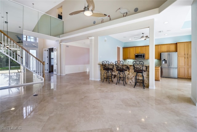 kitchen with a healthy amount of sunlight, stainless steel appliances, ceiling fan, and a breakfast bar area