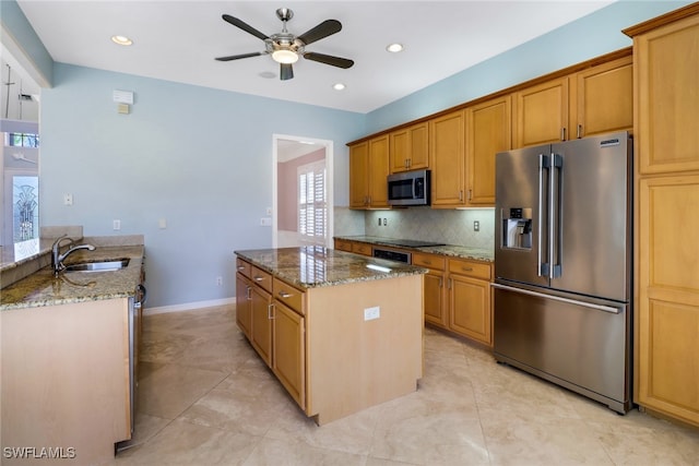 kitchen with light stone countertops, sink, stainless steel appliances, and ceiling fan