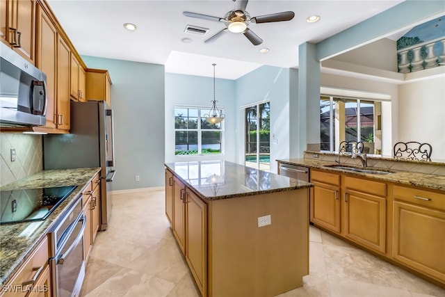 kitchen with dark stone countertops, a kitchen island, ceiling fan, decorative backsplash, and appliances with stainless steel finishes