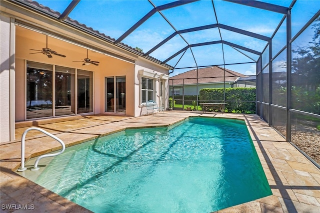 view of pool featuring glass enclosure, a patio area, and ceiling fan