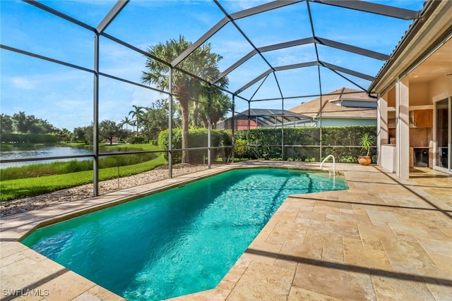 view of pool with glass enclosure, a water view, and a patio area