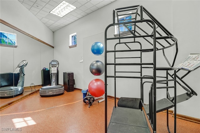 exercise area with a paneled ceiling and a towering ceiling