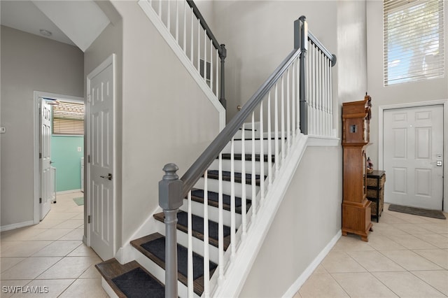 staircase with a towering ceiling and tile patterned floors