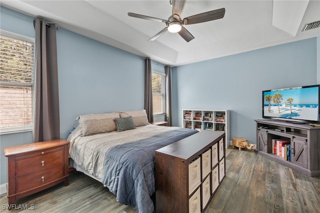 bedroom featuring ceiling fan, a raised ceiling, and dark hardwood / wood-style floors