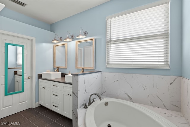 bathroom with dual vanity, a tub to relax in, and tile patterned floors