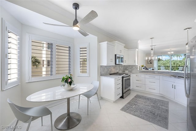 kitchen featuring appliances with stainless steel finishes, ornamental molding, hanging light fixtures, white cabinetry, and backsplash