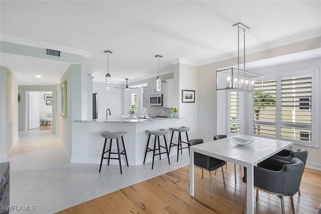 dining space with a wealth of natural light, visible vents, and crown molding