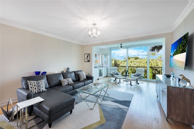 living room featuring light wood-style flooring, ornamental molding, a chandelier, and baseboards