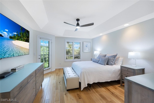 bedroom featuring access to exterior, a tray ceiling, recessed lighting, a ceiling fan, and light wood-type flooring